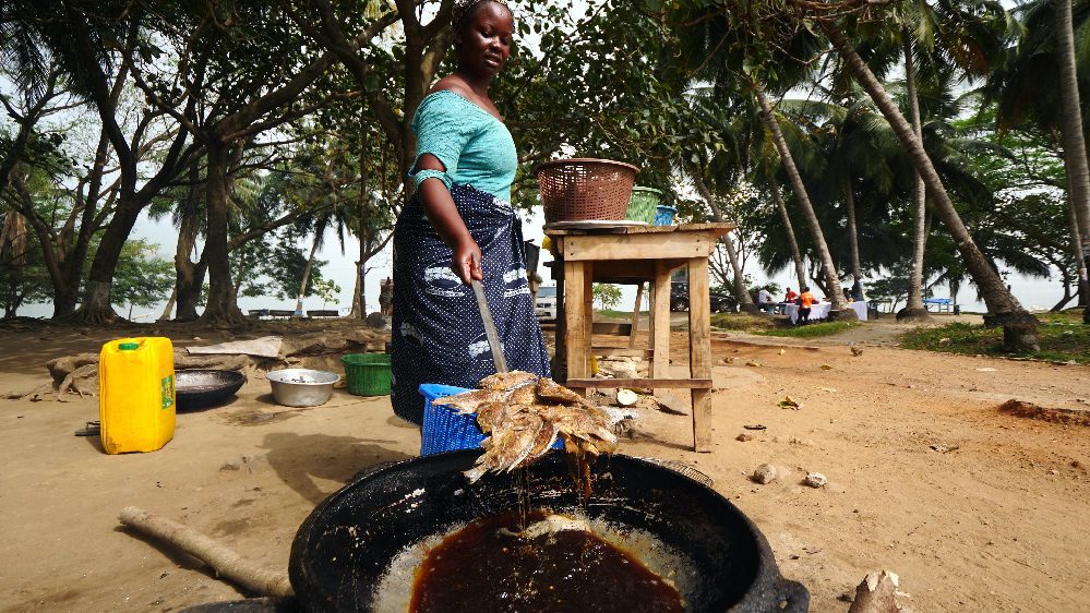 A woman cooking fanti kenkey and tilapia at Lake Bosomtwe, Ghana