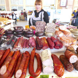 A vendor selling an assortment of meats and sausages at Privoz Market