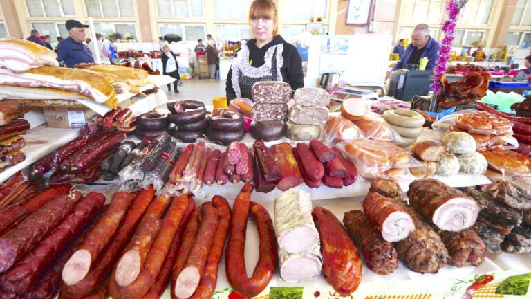 A vendor selling an assortment of meats and sausages at Privoz Market