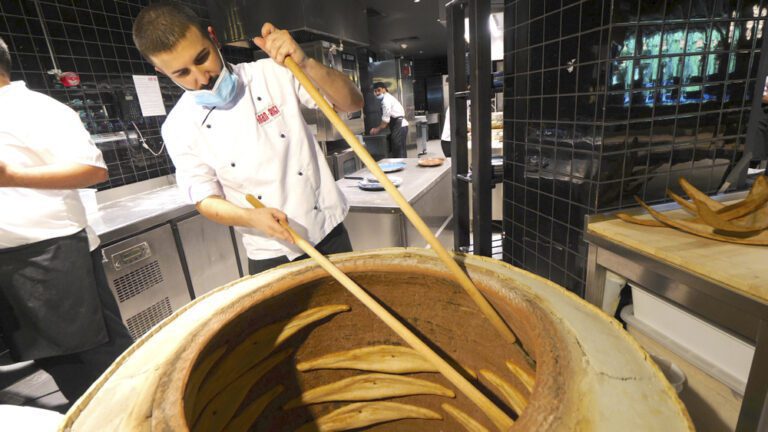 A cook baking dedas puri in a tonir oven in Rigi Restaurant