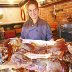 A waitress getting ready to serve suckling pig at Tamtaki Restaurant