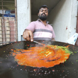 A street food vendor preparing masala vada pav in Mumbai, India