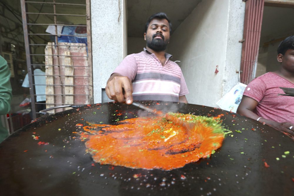 A street food vendor preparing masala vada pav in Mumbai, India