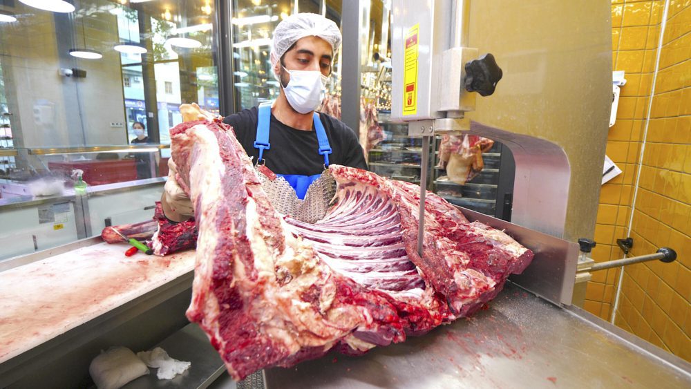 An employee slicing a large piece of raw meat at Tserti