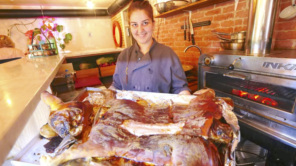 A waitress at Tamtaki holding a large plate of roasted pork