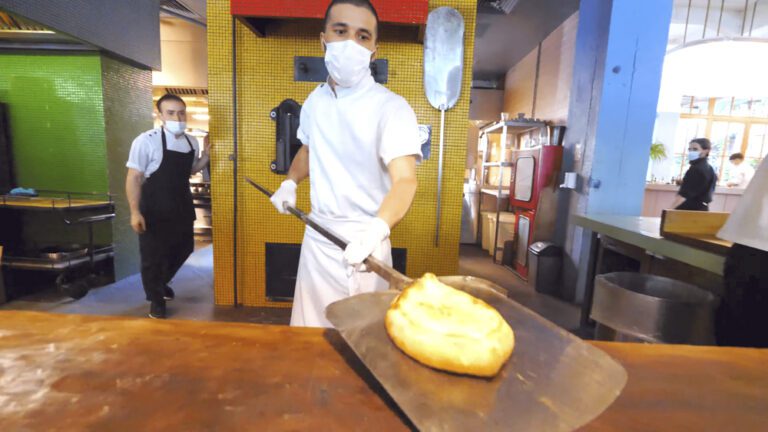 A cook at Stamba with a freshly-made Adjarian khachapuri