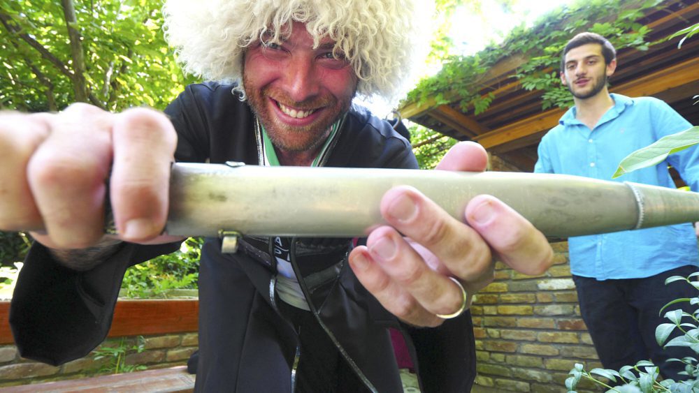 David Hoffmann posing with a traditional Georgian knife while wearing a traditional woolen coat and hat