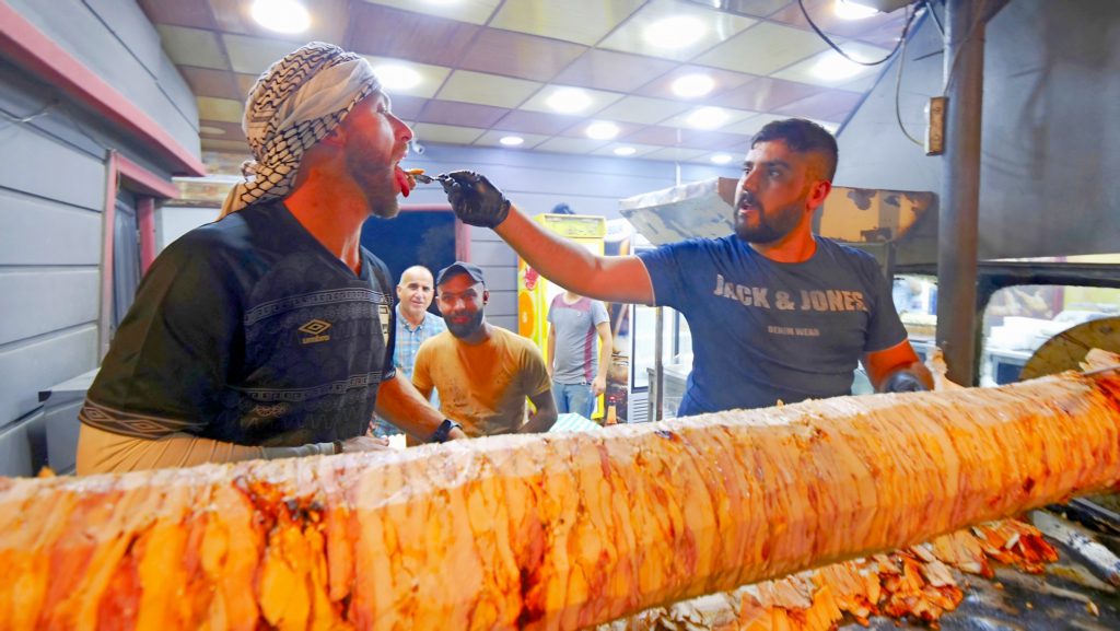 A friendly vendor feeding me fresh chicken shawarma straight from the spit | Davidsbeenhere