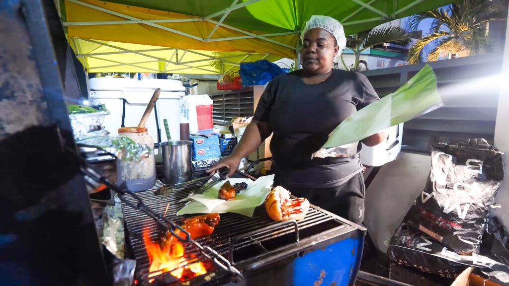 A woman grilling Barbados street food in Bridgetown | Davidsbeenhere