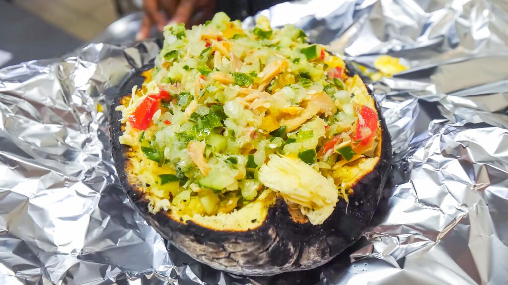 A charred breadfruit stuffed with saltfish buljol, pickles, cucumbers, tomatoes, sweet peppers, and lime juice | Davidsbeenhere