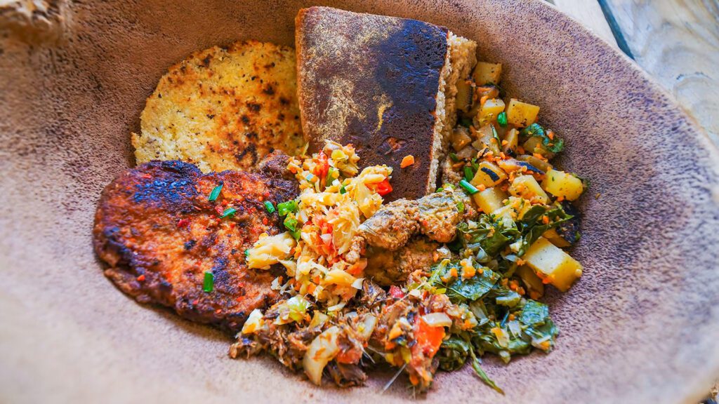 A calabash bowl filled with bakes, fried shark, saltfish buljol, herring, bhaji, and other Caribbean breakfast favorites | Davidsbeenhere