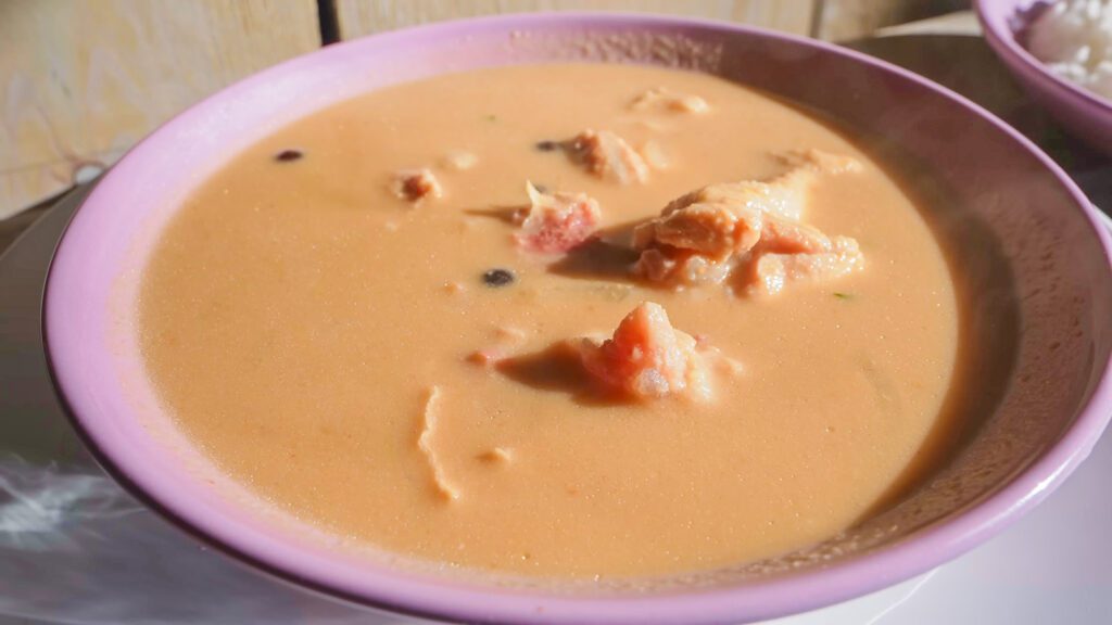 A lavender-colored bowl filled with pinda soup, a West African peanut soup that's a staple in Suriname food | Davidsbeenhere