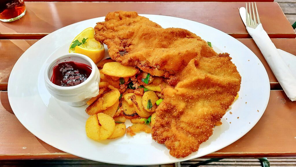 A plate of wiener schnitzel, made from veal, with lemon wedges and berry sauce | Davidsbeenhere