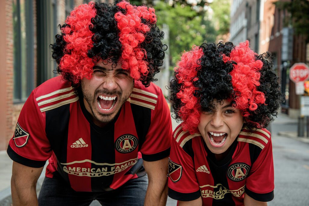 A man and a child dressed in colorful football jerseys and matching wigs | Davidsbeenhere