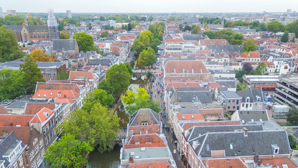 An aerial view of Utrecht, the Netherlands, including several homes, businesses, and churches near a tree-lined canal | Davidsbeenhere