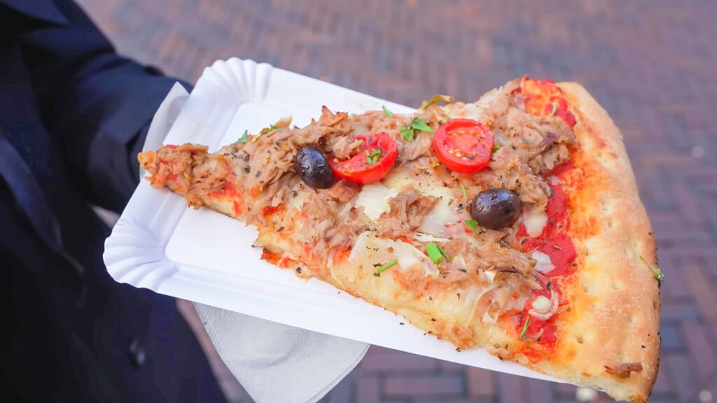 A slice of pizza from Broodje Mario that's topped with tuna, onions, artichokes, tomatoes, and olives | Davidsbeenhere