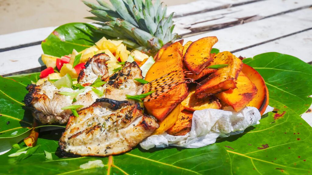 Barbecued lionfish (an invasive poisonous fish), barbecued breadfruit, and pineapple chow on a leaf in Tobago | Davidsbeenhere