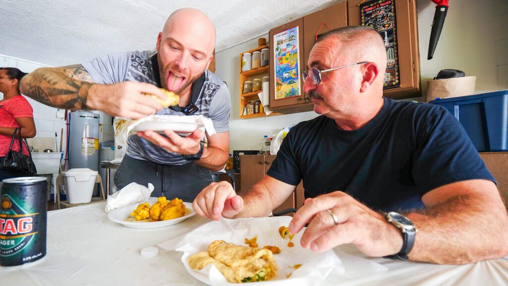 David Hoffmann demonstrates how to eat Trinidadian doubles to a fellow DesiVibes customer | Davidsbeenhere