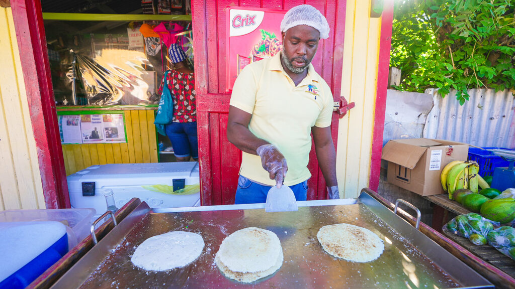 A Caribbean market vendor in Portsmouth, Dominica, grills flatbread made from cassava flour | Davidsbeenhere