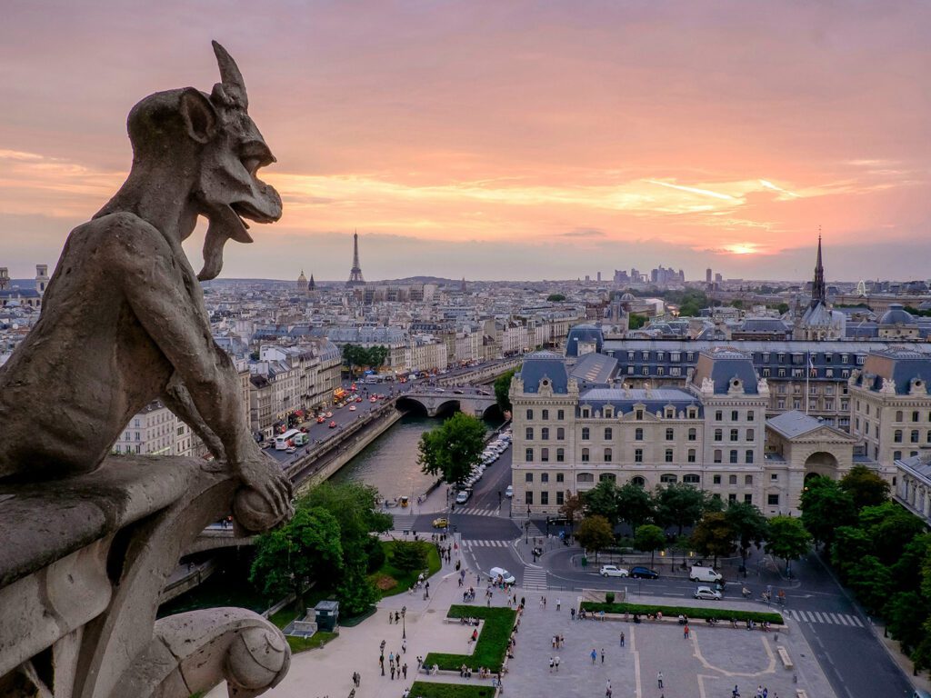 A stone gargoyle overlooks the city of Paris from atop Notre-Dame Cathedral | Davidsbeenhere